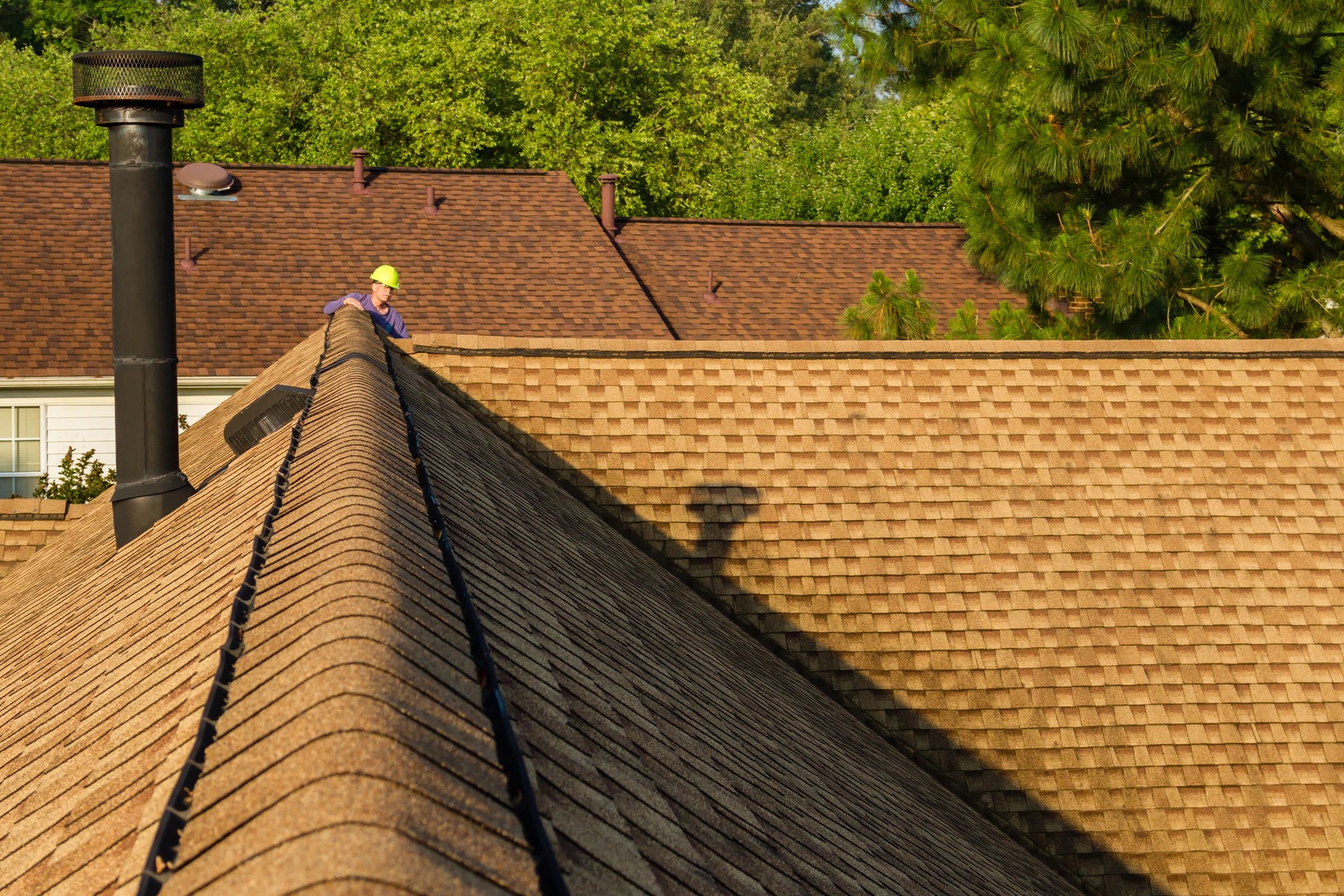 Roof inspector standing on a residential asphalt shingle roof